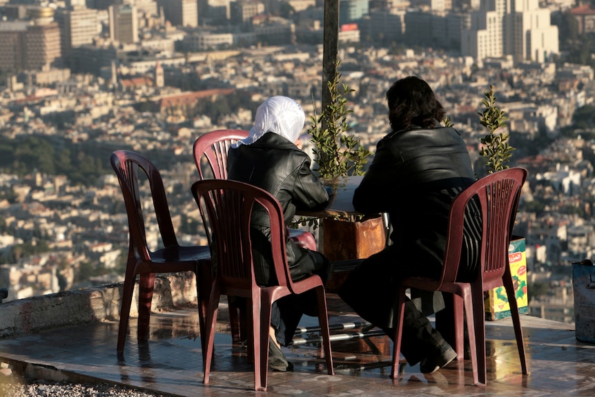 Couple sharing a meal on plastic table overlooking Damuscus Syria