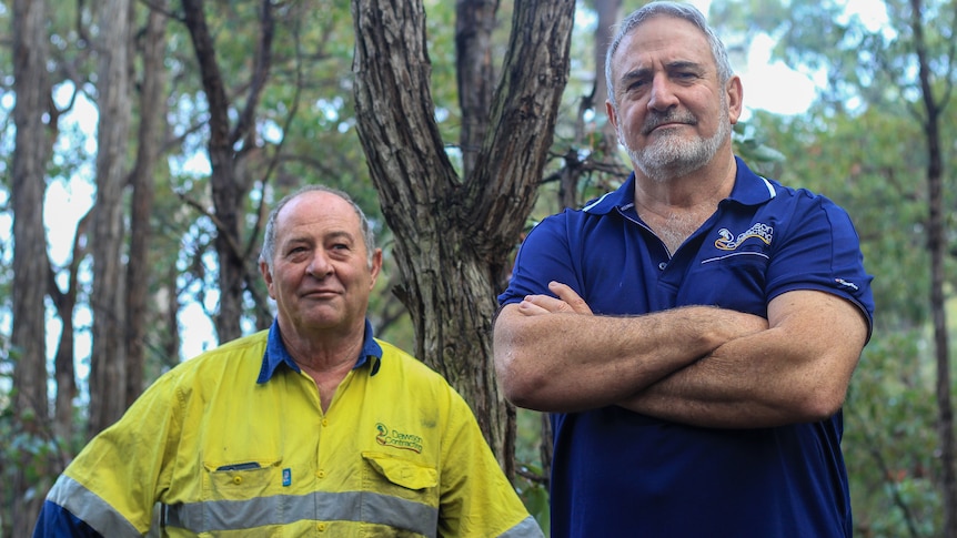 Daryl in high vis on left and Bernie wearing a blue polo shirt pose in front of bushland near Argyle, WA. 