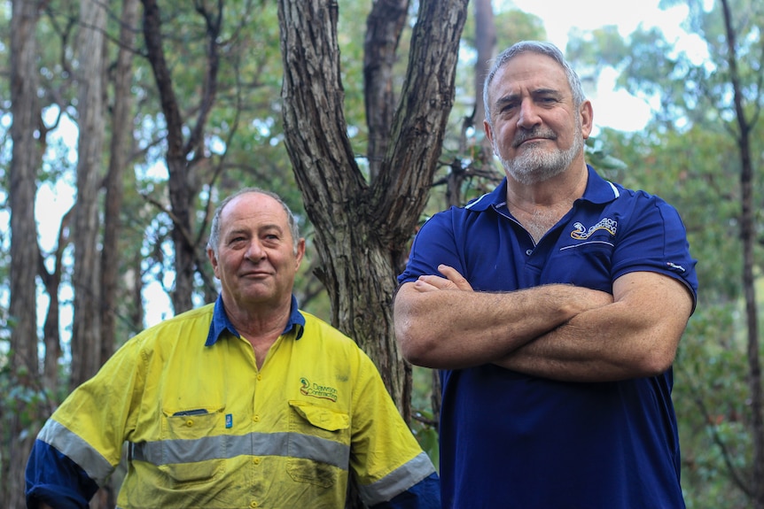 Daryl in high vis on left and Bernie wearing a blue polo shirt pose in front of bushland near Argyle, WA. 