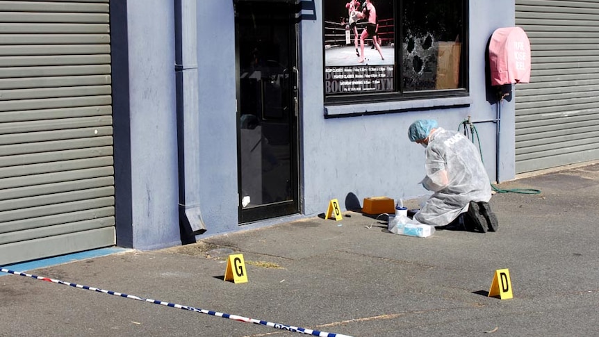 A police forensics officer works at the scene of a shooting at the Boonchu Gym at Burleigh Heads.