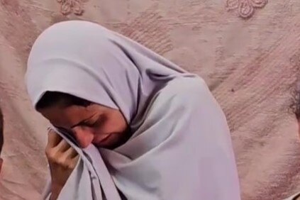 A woman in a white hijab crying