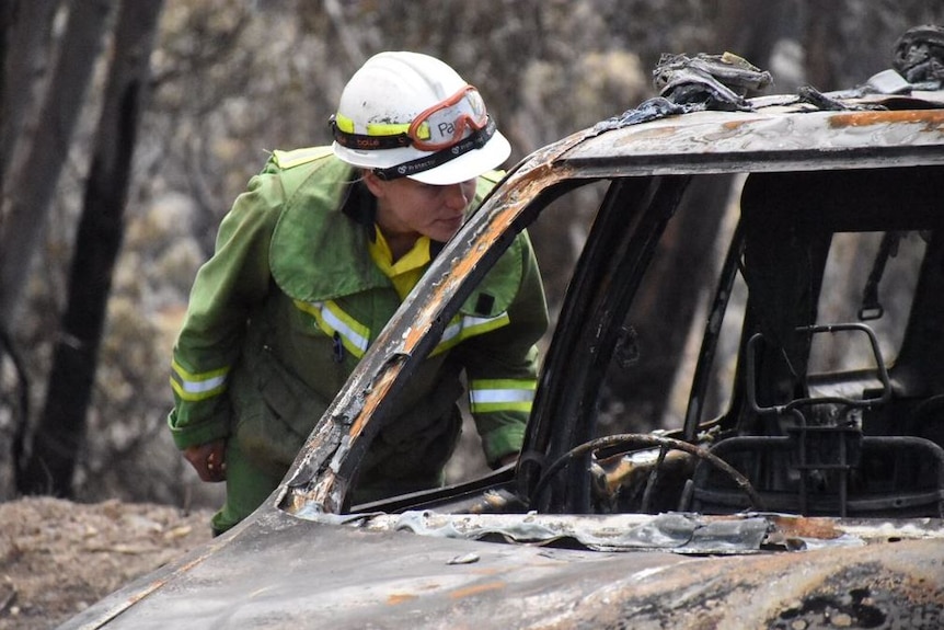 A firefighter inspects a burnt car.