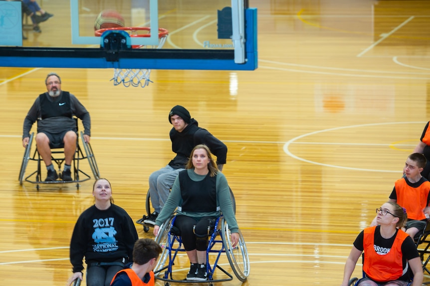 All players on court looking up at the ball travelling towards basket in a wheelchair basketball game