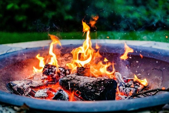 wood-fired fire pit with logs buring with yellow flames 