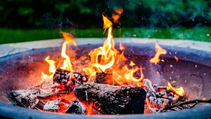 wood-fired fire pit with logs buring with yellow flames 