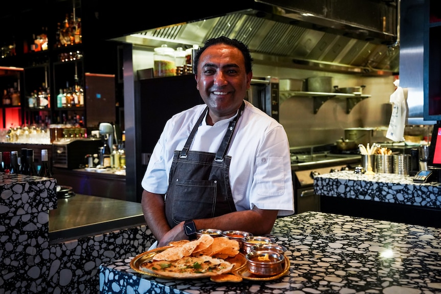 Jessi Smith poses for a portrait, while an Indian dish rests on a bar countertop