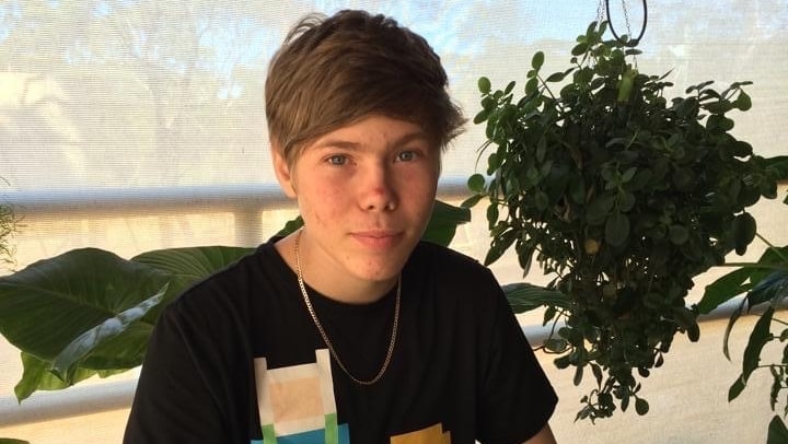 A young man wearing a dark T-shirt and a chain.