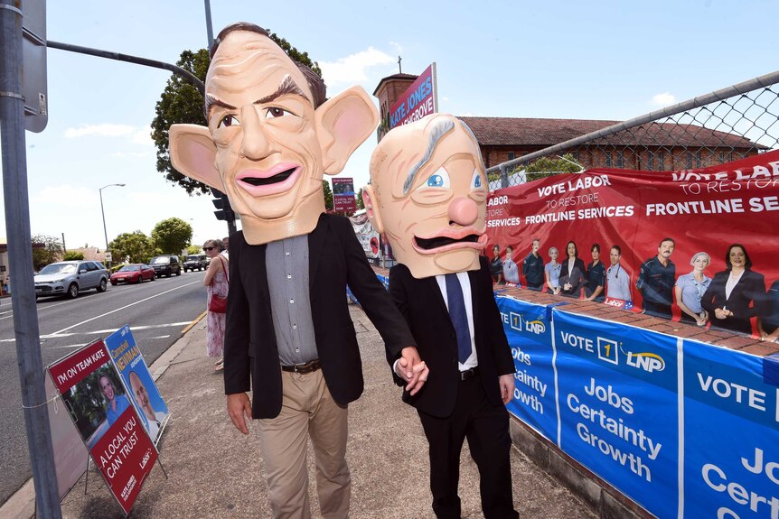Giant figurines of Mr Newman (right) and Prime Minister Tony Abbott walk hand in hand outside a polling booth in Ashgrove.