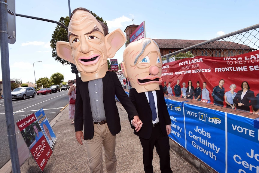 Giant figurines of Mr Newman (right) and Prime Minister Tony Abbott walk hand in hand outside a polling booth in Ashgrove.