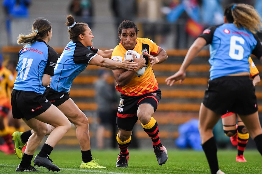 Elsie Albert has the ball and is running hard as a Fiji player tries to tackle her.