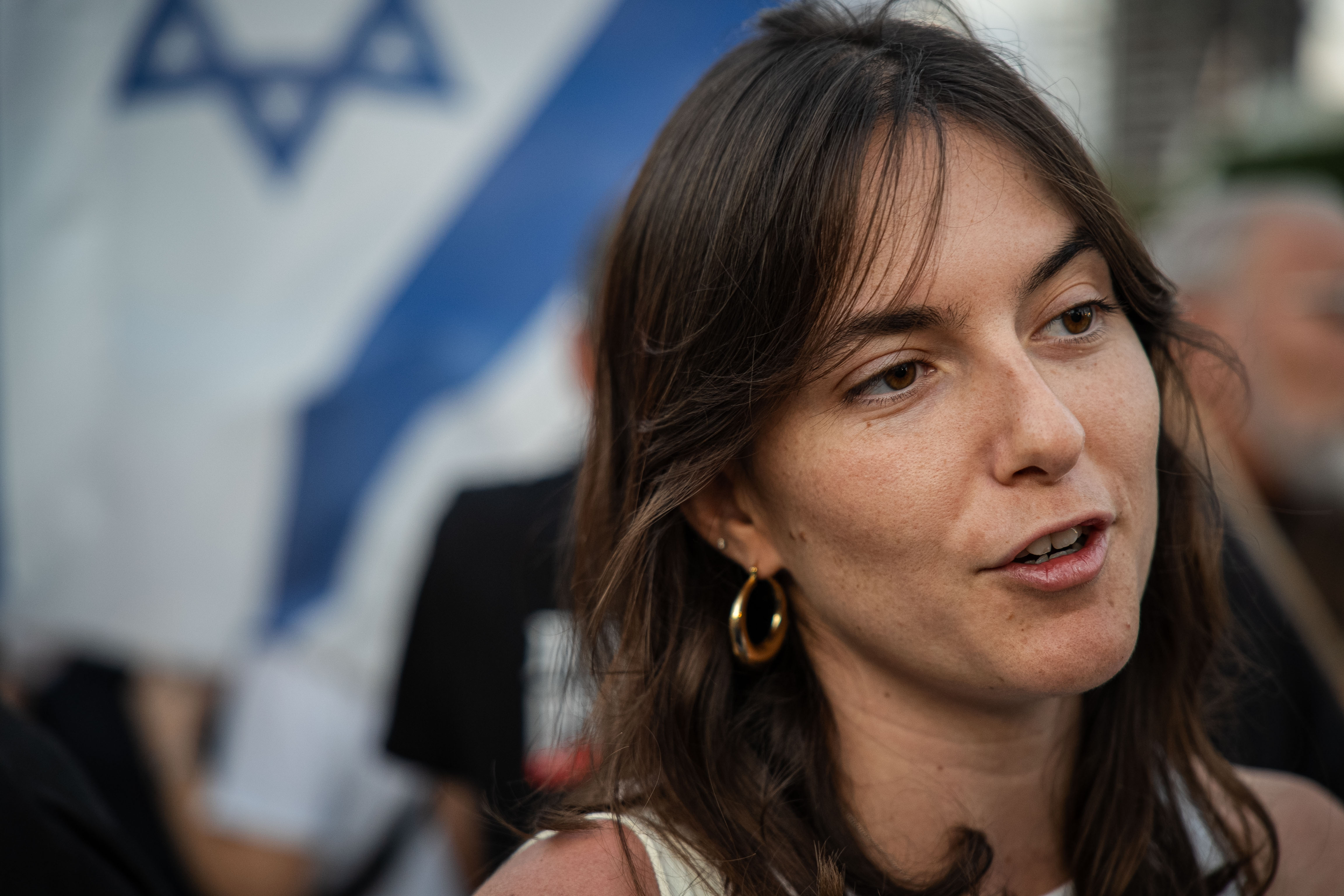 A close up of a young woman with the israeli flag behind her