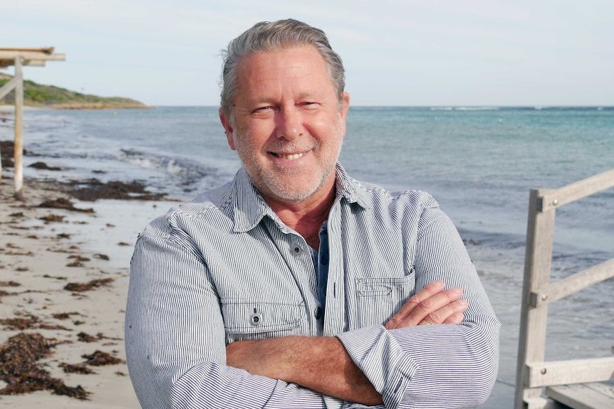 Bradley Farmer stands on beach smiling.