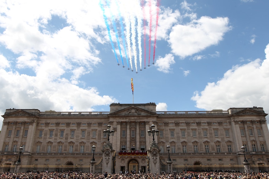 Nine planes with coloured smoke trails fly over Buckingham Palace.