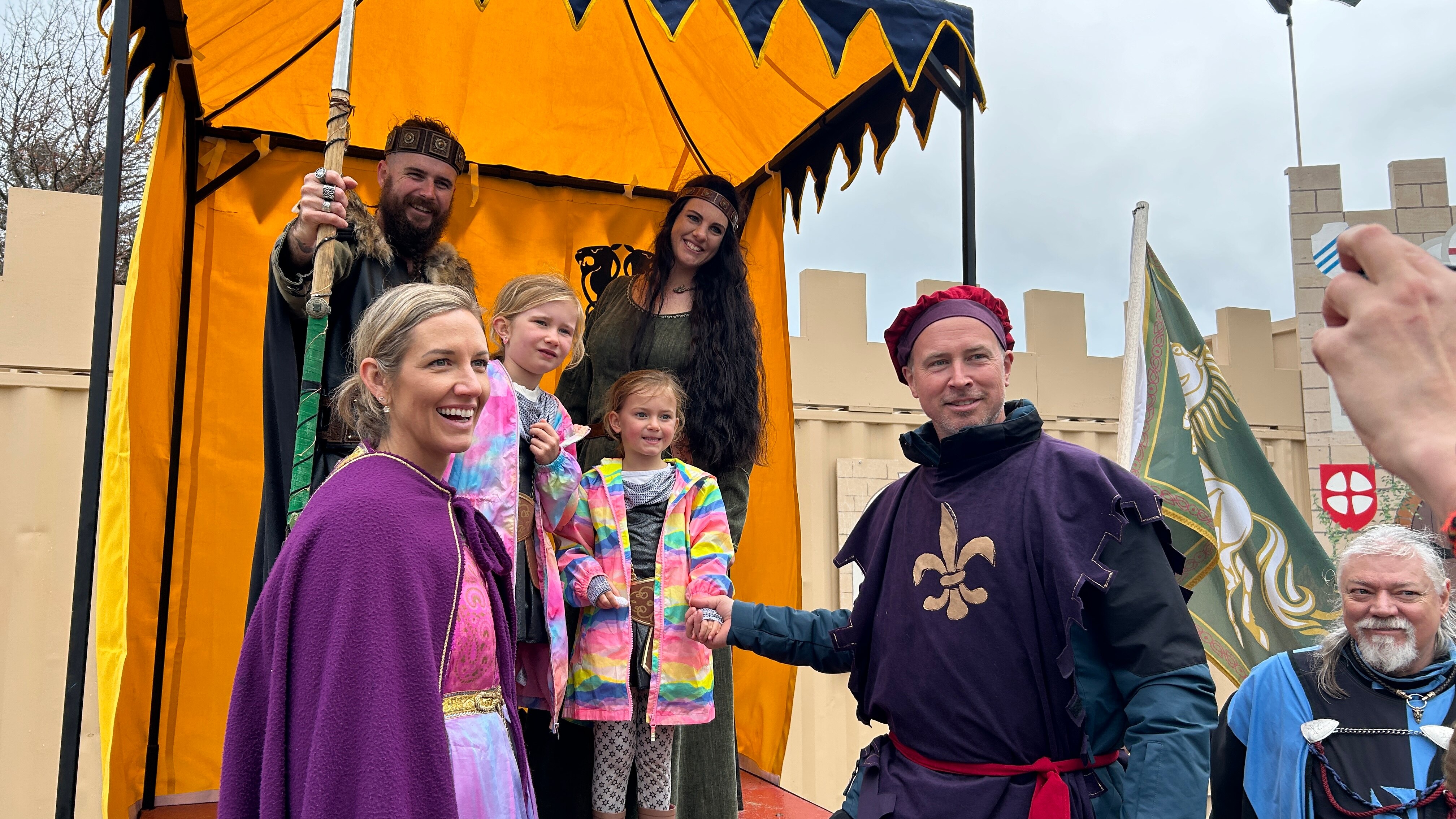 People dressed up in medieval costumes, with a "king and queen" in the background on a throne.
