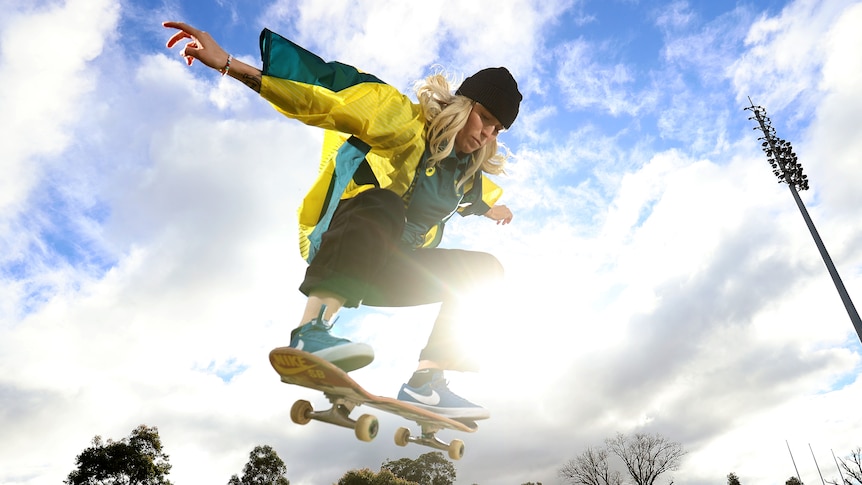 Australian skateboarder Hayley Wilson in the air on her board, wearing a beanie and a Tokyo Olympics kimono.