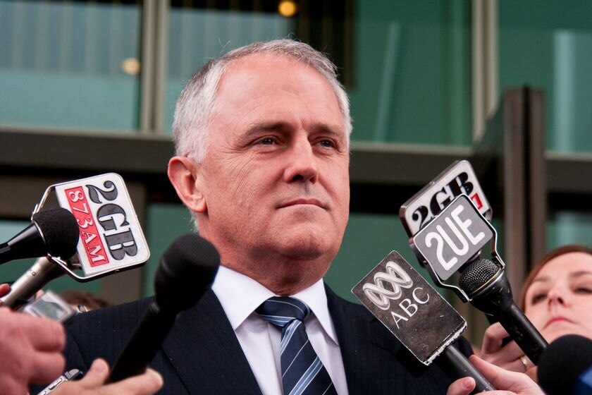 Malcolm Turnbull, surrounded by news microphones, stares with steely resolve.