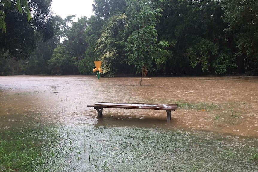 A park bench in a park going under flood waters