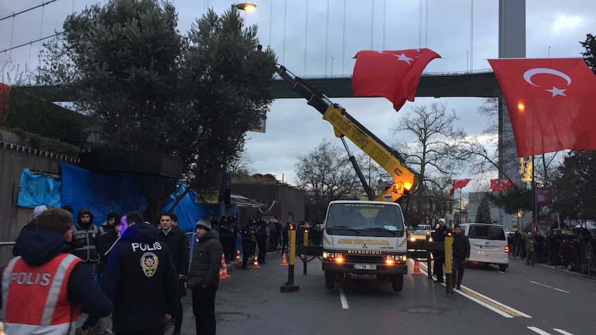 Police stand outside the Reina nightclub, Instanbul, as the Turkish flag waves in the breeze.