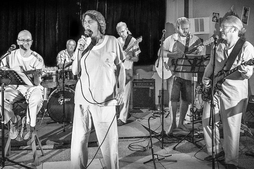 A band comprised of medical professionals rehearses in a black and white image.