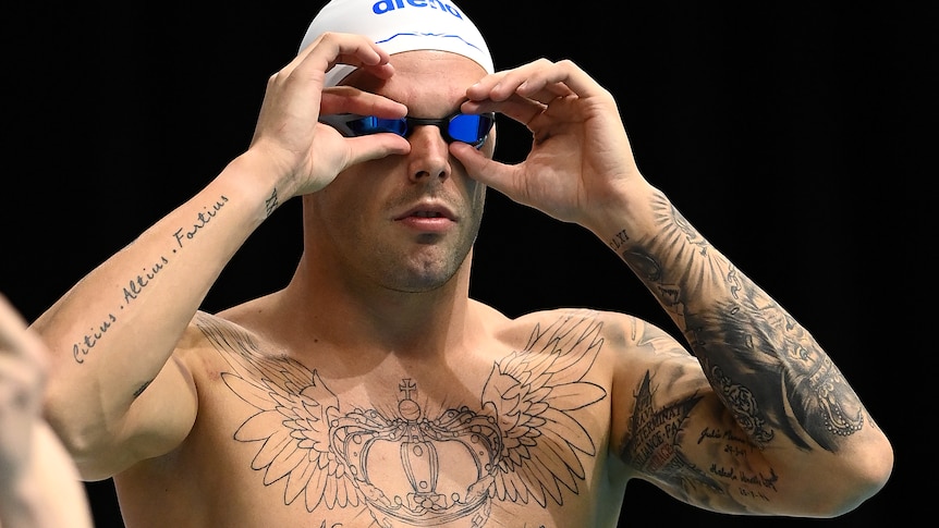 Kyle Chalmers adjusts his goggles with his hands as they sit on his face