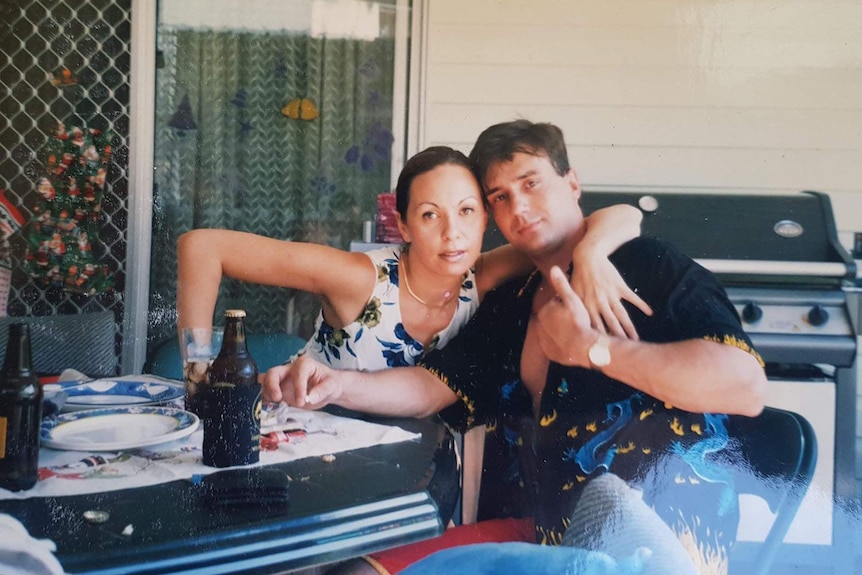 Cinamon and David Murphy hug while sitting at a table, date and location unknown.