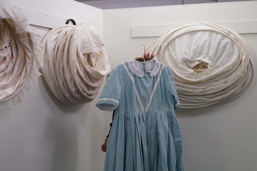 A mid-19th century blue dress on a hanger