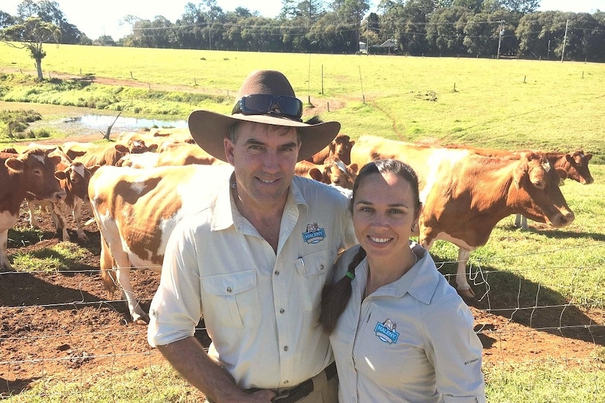 Ross and Sally Hopper smile at the camera surrounded by cows.