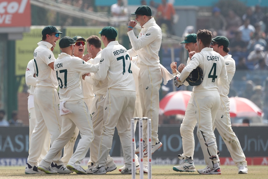 Australian cricketers surround bowler Matthew Kuhnemann in jubilation after his dismissal of former Indian captain Virat Kohli.
