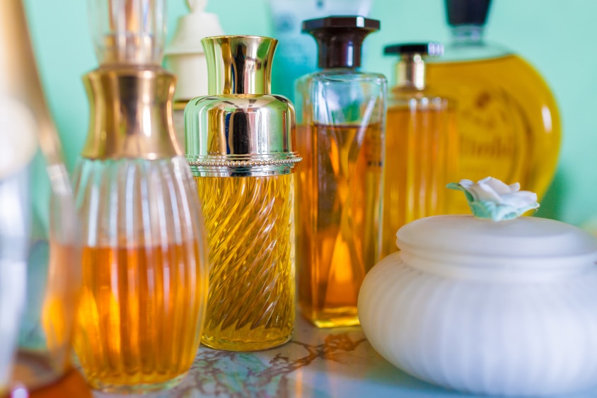 A collection of perfume bottles lined up on a marble bench.