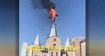 A still from a video shows a cross at the top of a church on fire.