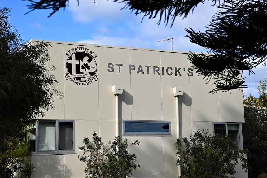 A white school building with a sign reading St Patrick's in black letters.