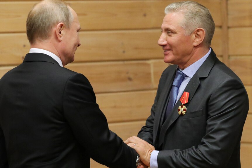 Vladimir Putin shakes hands with Boris Rotenberg