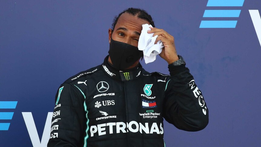 F1 driver Lewis Hamilton wipes his brow while standing on the podium after Russian Grand Prix in Sochi.