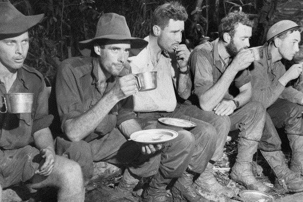 Wounded soldiers from the Battle for Gorari in Papua New Guinea eat and drink on their way back to Kokoda.