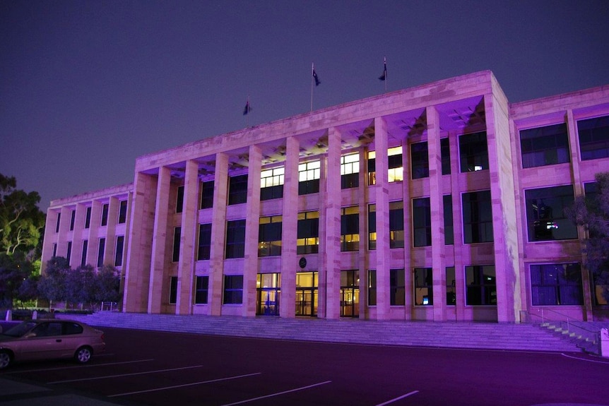 A wide shot of the front steps of Parliament House in Perth at dawn, with the building appearing purple in the morning light.