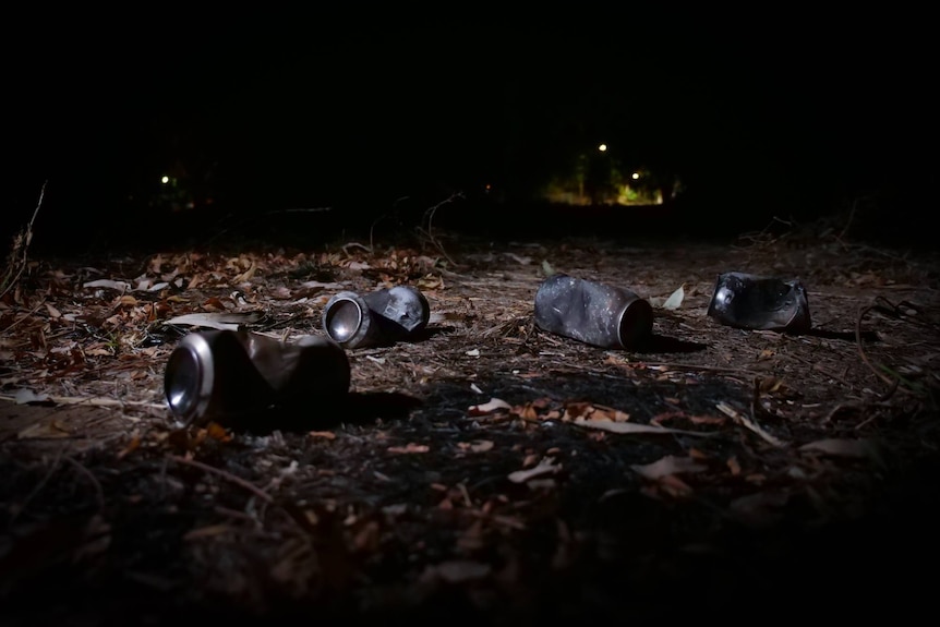 Several burnt drink cans lay on the ground.