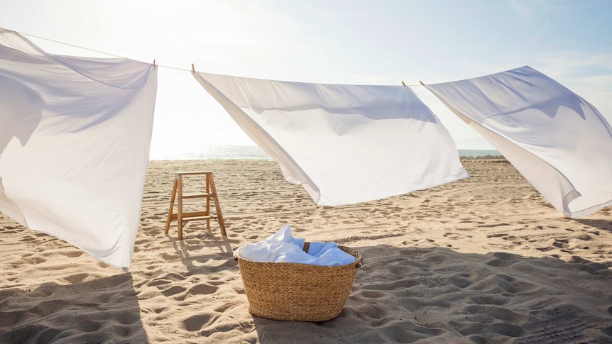 white sheets hanging on laundry line at beach