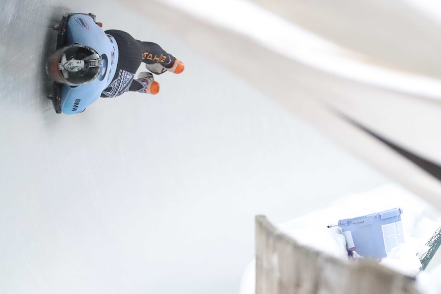 Nathan Crumpton sideways as he goes around a corner during a skeleton run.