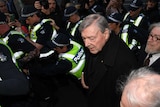 George Pell, surrounded by police, as he arrives at court in Melbourne