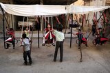 Syrian children play on swings, made from the remnants of exploded rockets in the rebel-held town of Douma.