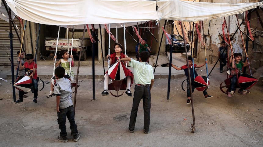 Syrian children play on swings, made from the remnants of exploded rockets in the rebel-held town of Douma.