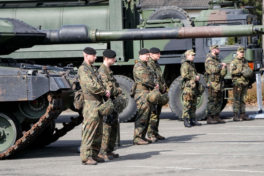 German soldiers stand in front of Leopard tanks. 