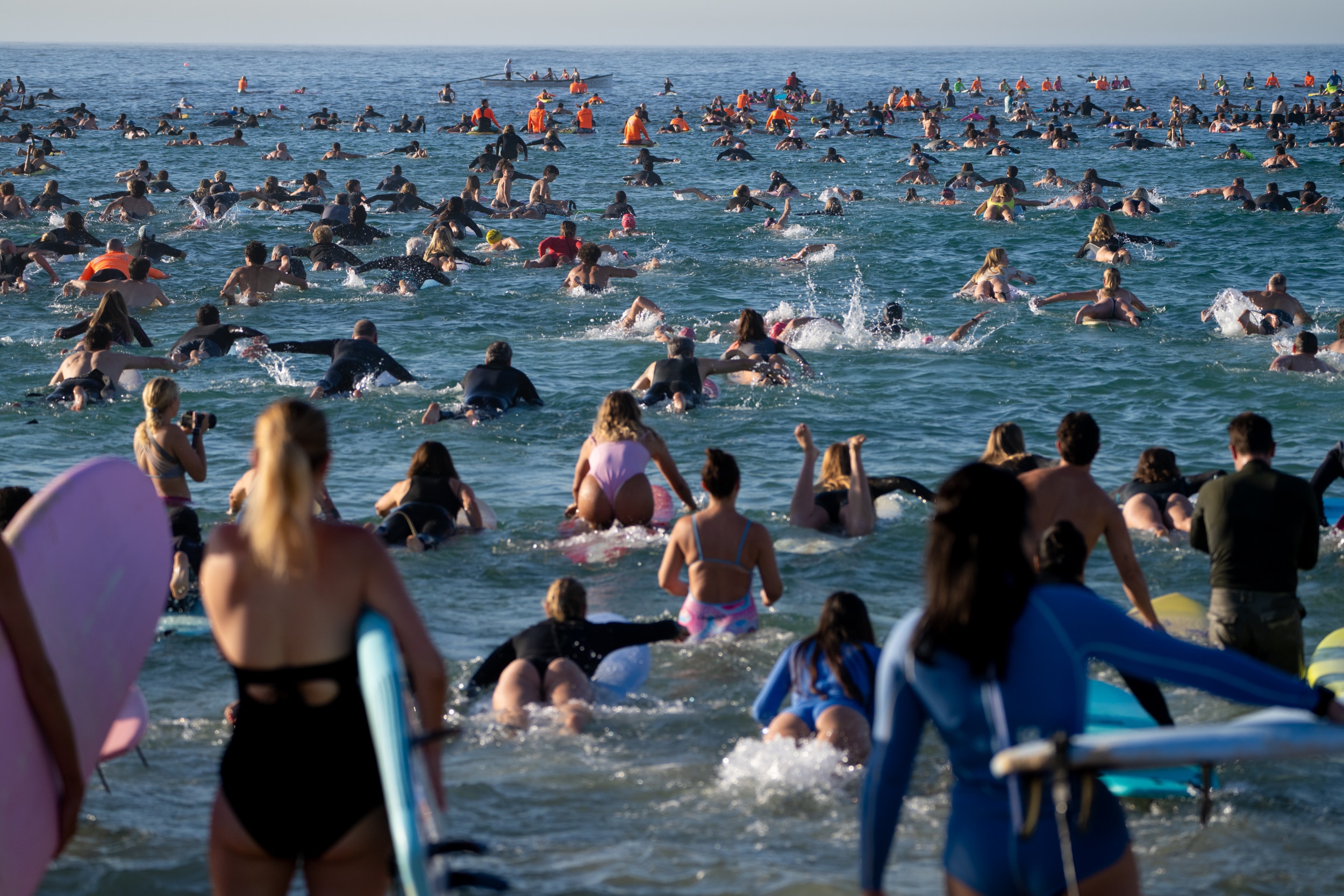 La gente camina con sus tablas hacia el agua en Bondi.