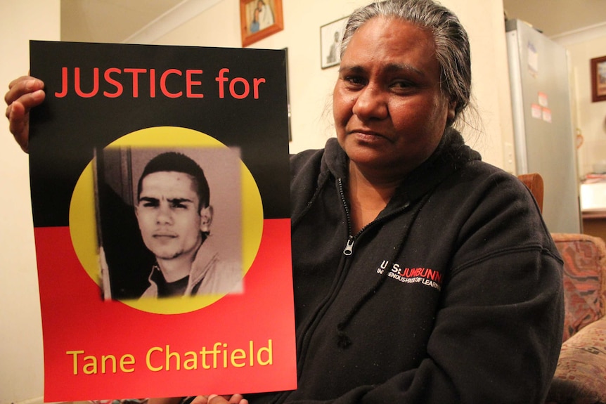 Nikoa Chatfield holding a sign demanding justice for her son, Tane