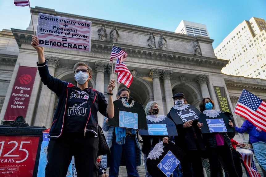 Demonstrators attend a rally outside the New York Public Library holding signs that say all votes must be counted.