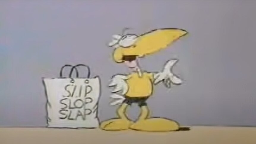 1980s Cancer Council mascot Sid the Seagull stands next to a tote bag with "slip slop slap" written on it.