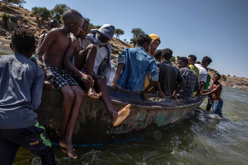 Refugees fleeing conflict in Ethiopia's Tigray on a boat crossing the river into Sudan