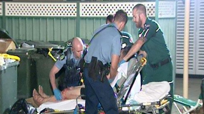 A man on a stretcher surrounded by police and paramedics.