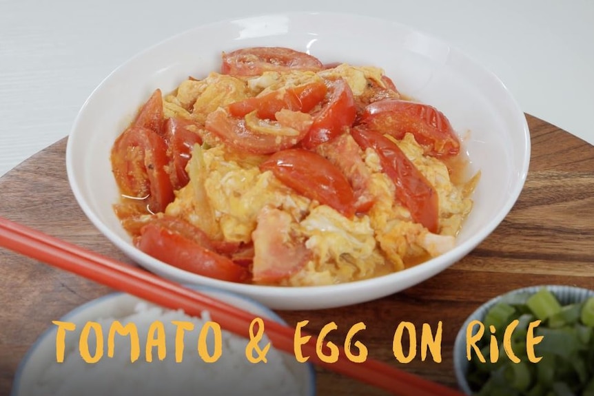 A white bowl filled with tomato and scrambled eggs.