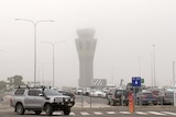 An airport tower in fog and a car park